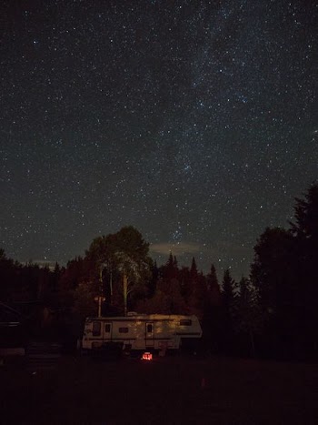 white RV trailer surrounded by trees during nighttime