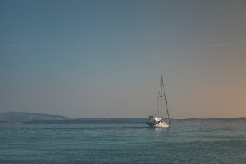 White Sailboat on Body of Water Under White Sky
