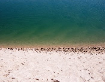 white sand near green calm body of water at daytime
