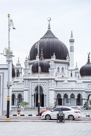 White Sedan Parked Beside White and Black Mosque