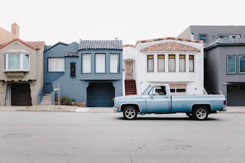 white single cab on road near blue and white houses