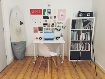 white surfboard beside white wall white wooden cube bookshelf inside the room