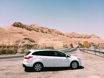 White Suv on Dirt Road Near Rock Formation