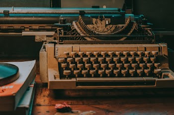 White Typewriter Near Pile of Books
