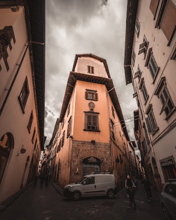 White Vehicle Parked Beside Building Near People Walking on Street