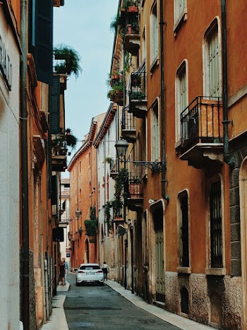 White Vehicle Passing by Alongside Brown Buildings