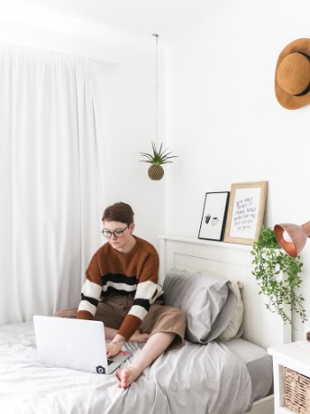 White woman working on bed with book and laptop 1