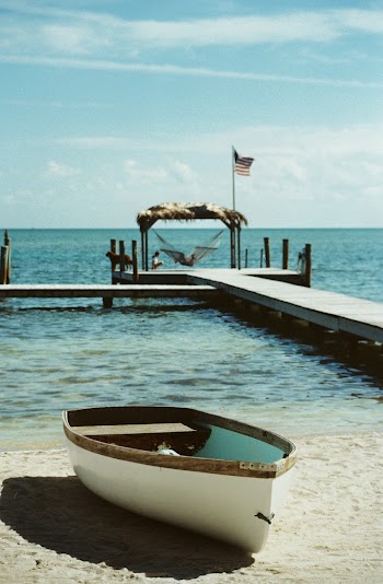White Wooden Canoe Near Seashore Under White and Blue Sky