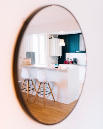 White Wooden Table and Chairs Seen from Oval Mirror