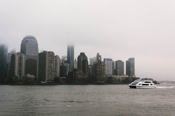 White Yacht Near High-rise Buildings Under the Cloudy Sky
