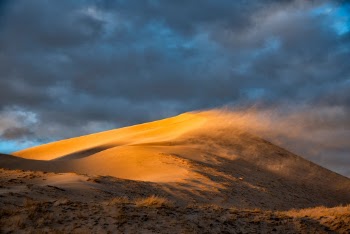 Wind at sunset creates blowing sand at the Kelso Dunes in Mojave National Preserve, California.