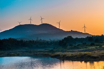 Windmills in Mountain Viewing Lake Under Orange Skies