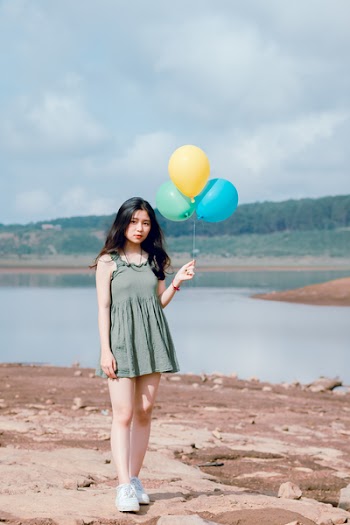 Woman's in Green Sleeveless Dress Holding 3 Balloons
