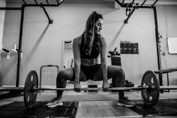 Woman About to Lift a Barbell Off the Floor Inside Gym