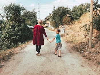 Woman And Boy Holding A Stick While Walking