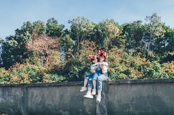 Woman and Girl Sitting on Concrete Wall