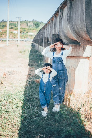 Woman and Girl Standing Beside Concrete Wall
