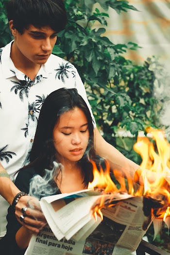 Woman and Man Holding Burning newspaper 