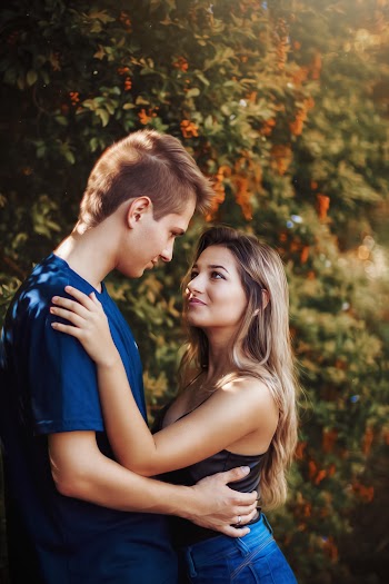Woman and Man Staring at Each Other While Standing Near Green-leafed Bushes