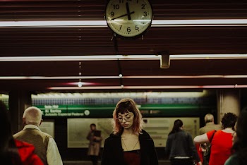 Woman and Men Standing Below A Clock a