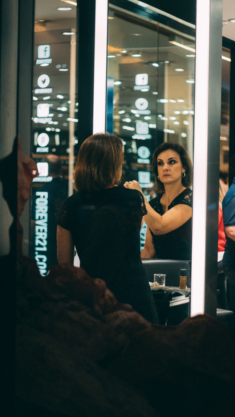 Woman Applying Makeup in Front on Vanity Mirror