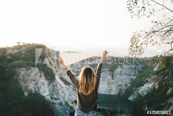 Woman arms raised and holding flag on mountain