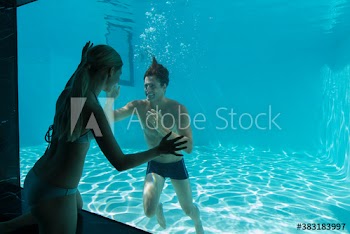 Woman at window watching boyfriend swimming underwater