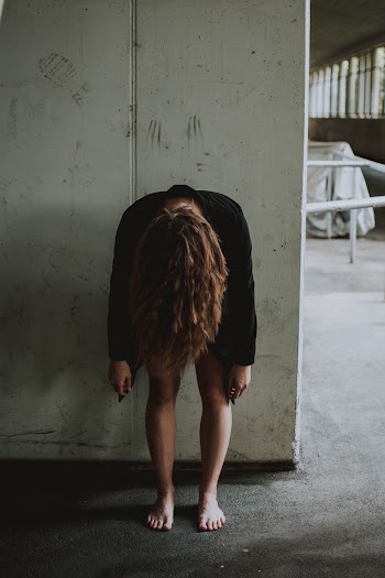 Woman Bending Forward While Leaning on Wall