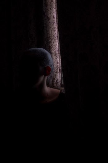 woman beside brown window curtain