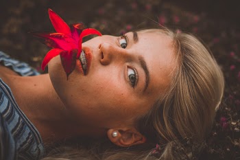 Woman Biting Flower While Lying on Grass