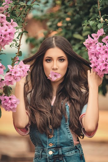 Woman Biting Pink Flower While Holding Her Hair