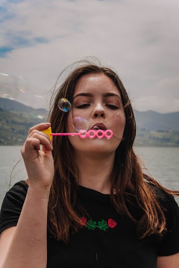 Woman Blowing Bubbles Using Pink Plastic Bubbler