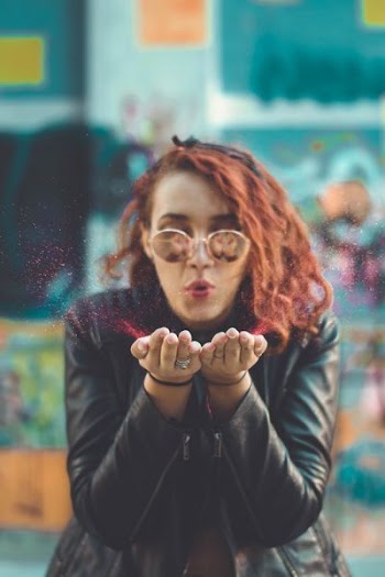 woman blowing red powder from her hands