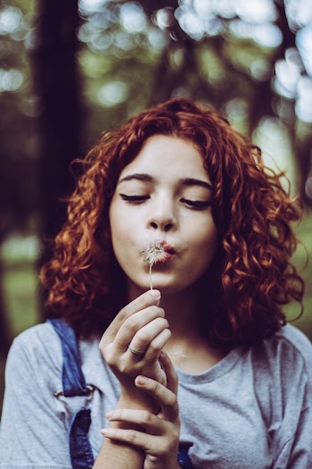 Woman Blowing White Dandelion Flower
