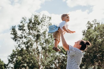 Woman Carrying Baby Near Green Trees