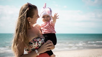Woman Carrying Baby On Shore 