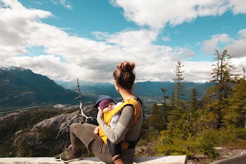 Woman Carrying Baby Sitting on Gray Surface