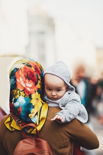 Woman Carrying Baby While Walking on the Street