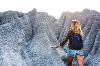 woman carrying backpack standing near rocks