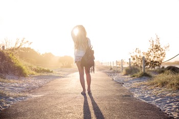 Woman Carrying Backpack Standing On Asphalt Road During Golden Hour