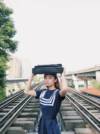 Woman Carrying Bag at Head Standing on Railway