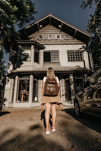 Woman Carrying Brown Leather Backpack Standing In Front Of A Building
