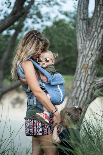 Woman Carrying Child in Carrier While Standing Beside Girl