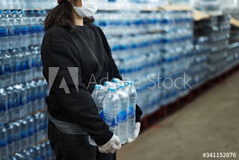 Woman carrying drinking waters with gloved hands during coronavirus pandemic