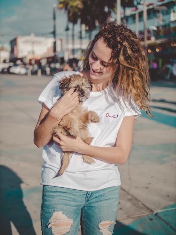 woman carrying long-coated beige puppy