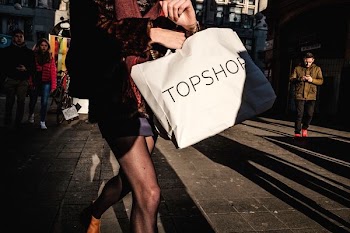 woman carrying white TopShop paper bag near man wearing brown jacket