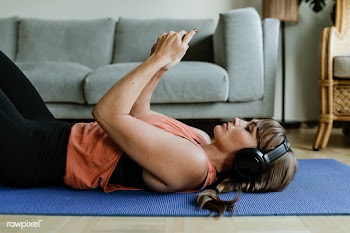Woman choosing music from her phone while lying on a yoga mat during c.. | Free  photo - 2310155