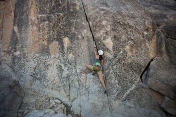 woman climbing on rock cliff during daytime