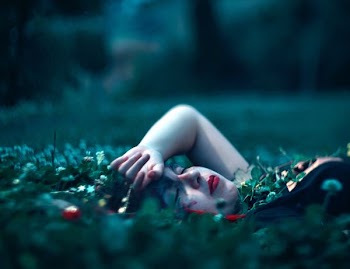 woman closing eyes lying on green grass