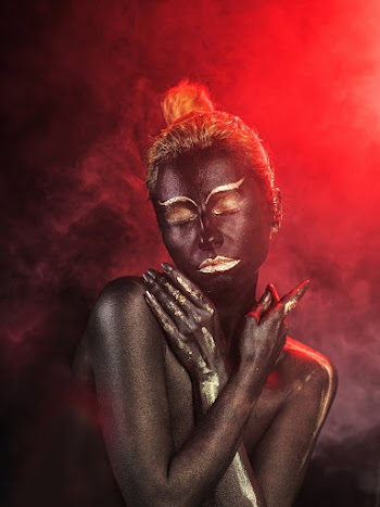 Woman Covered by Black Paint Against Red Light